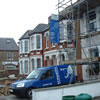 external picture of loft conversion company working on a house with scoffolding in london